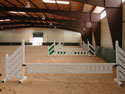 This indoor steel-riding arena is part of a 4 building complex equestrian center.  The riding arena is used primarily for hunter jumper and dressage and due to the roof skylights and wall lites, boasts a very bright and cheerful riding environment.